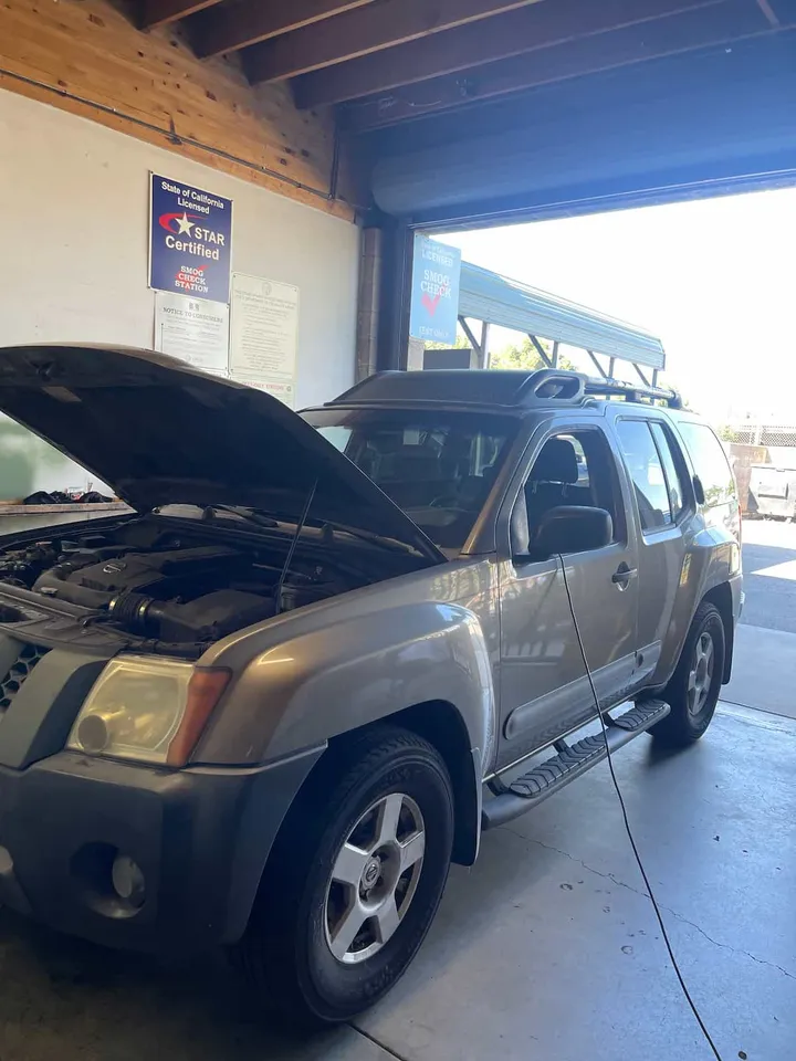 An SUV in the Smog Junkies SMG test bay, with the State of California STAR Certified sign on the wall